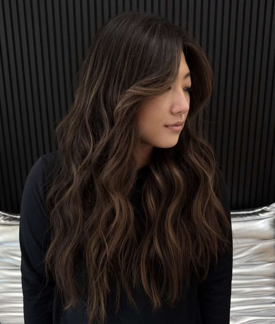 Long dark brunette waves against a slatted wall